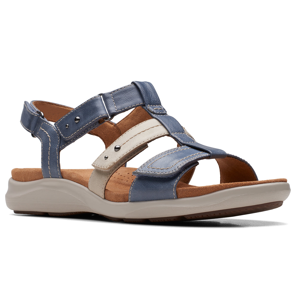 A pair of women's flat sandals with adjustable straps in blue, beige, and brown colors, featuring a rubber outsole. Kitly step in denim by Clarks.