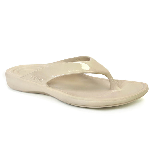 Ivory gloss flip-flop sandal with contoured footbed, soft toe post, and subtle shine. Made from single-piece UltraSky™ EVA foam with arch support and water-friendly construction for stylish pain relief in warm weather. Style #L31033W