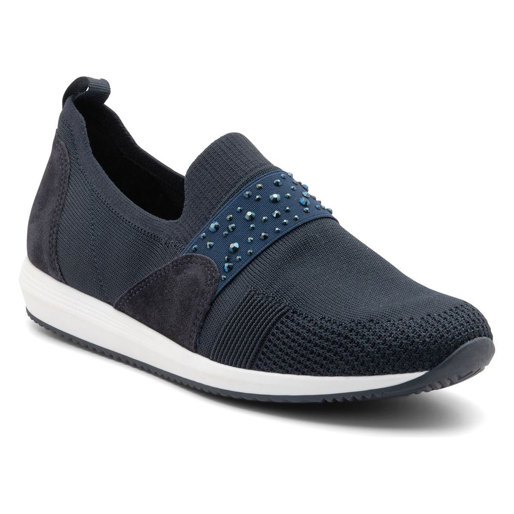 Women’s slip-on sneaker in black stretch-knit fabric with rounded toe, elasticized topline, and subtle heel tab. Features a cushioned removable insole, flexible shock-absorbing sole, and a sleek, minimal design for versatile everyday wear. Style #14003-02