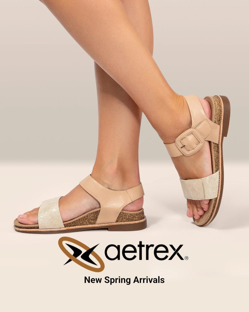 Beige sandals worn by a person on a light background with Aetrex branding.