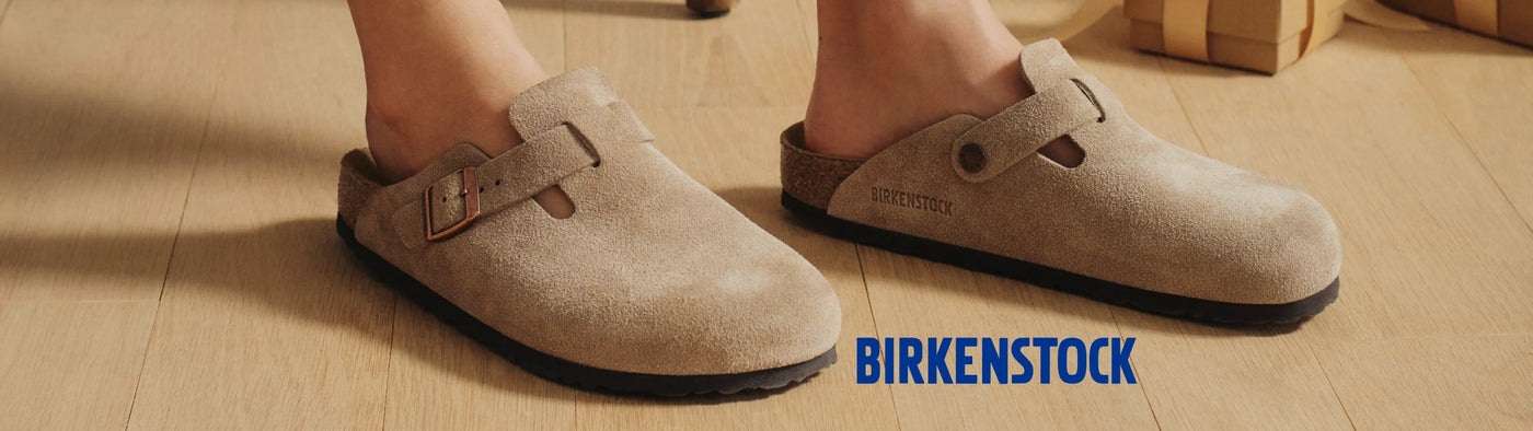 Beige Birkenstock shoes on a wooden floor with the brand name visible.