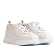 Off-white leather low-top sneaker with a flared wedge sole and lace-up front, blending sporty comfort with minimalist European design. Style #A2424-0350